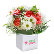 There's a lively, uplifting spirit woven into every aspect of this Honor Oak bouquet, elegantly arranged in a flawless white gift bag-ready to bring a pop of freshness to any occasion. Plush coral and red carnations form the dazzling heart of the display, their soft, frilly petals bursting with cheerful energy, reminiscent of the first blooms spilling out along Brockley's side streets each spring. Bright white daisies with golden-green centers sit playfully alongside, creating a sunlit feeling, while flecks of delicate baby's breath float through, adding a dreamy, cloudlike texture. Sleek, deep green leaves gently cradle the florals, and to the left, closed buds with a subtle purple tint promise new growth and delight. The bouquet is designed to be easy to carry and present, making it perfect for doorstep surprise celebrations, from Honor Oak Park to Blythe Hill. Photographed against a radiant white background, every petal and leaf shimmers with the promise of joy and warmth-ideal for marking life's milestones or simply sending a smile across Honor Oak.